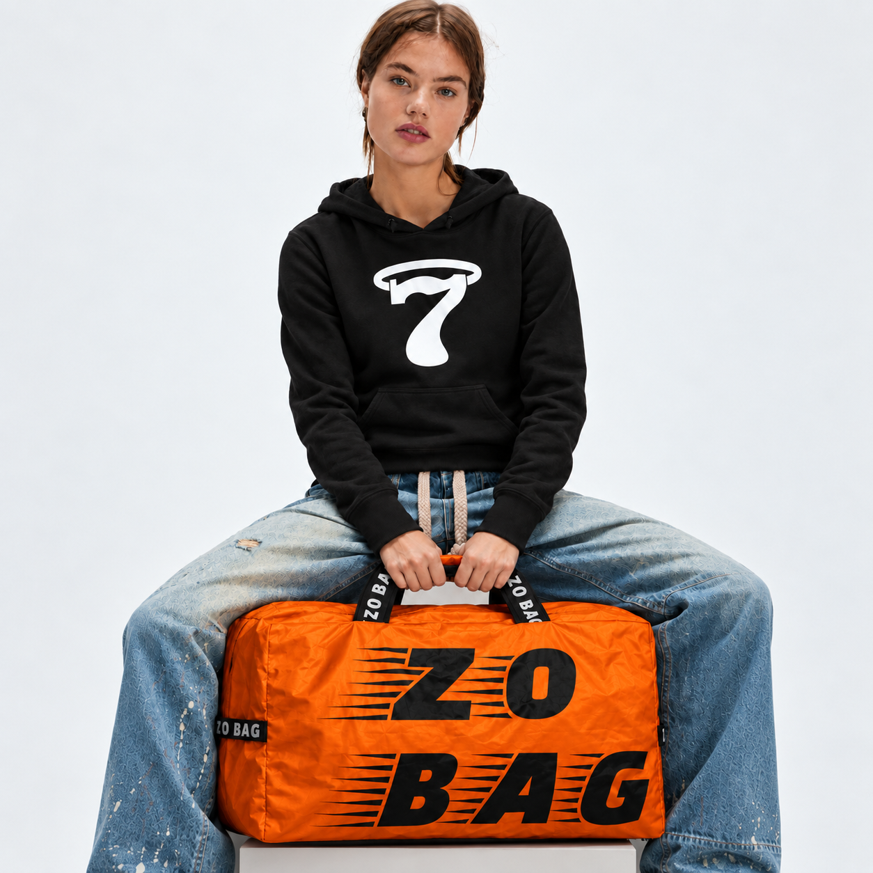 Woman seated with the orange Zo Bag